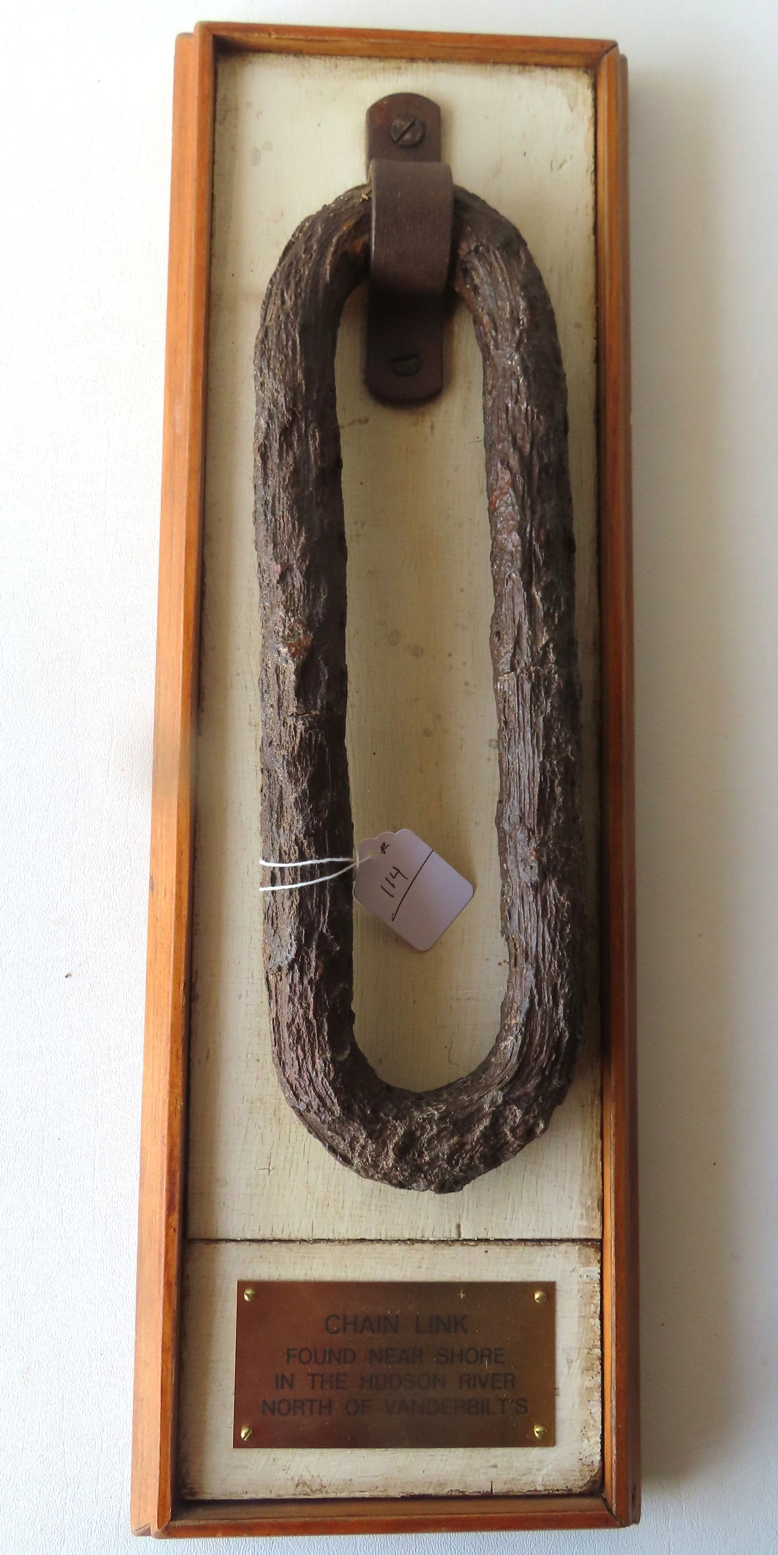 A wall plaque with an attached rusted chain link marked "Chain link found near shore in the Hudson (1 of 2)