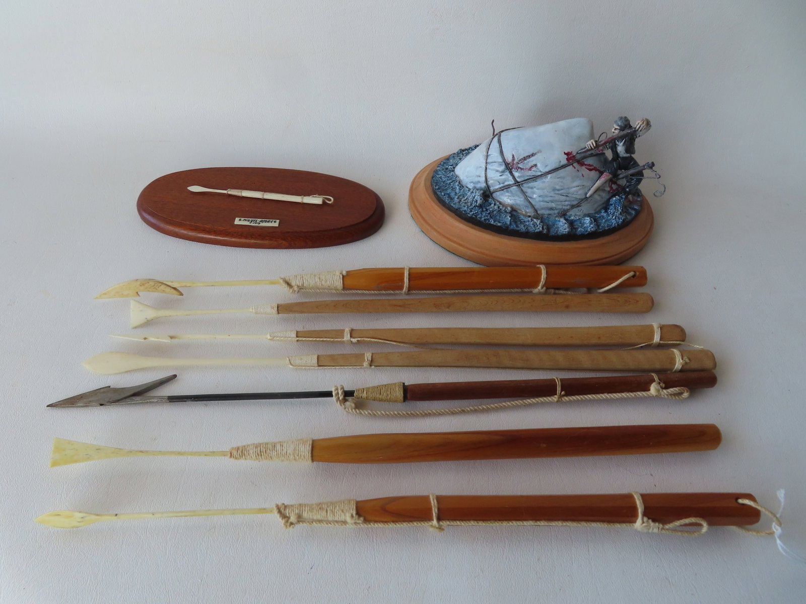 Grouping of 8 miniature harpoons - the largest 15"L; and a ceramic sculpture depicting a wooden leg: Grouping of 8 miniature harpoons - the largest 15"L; and a ceramic sculpture depicting a wooden leg sailor harpooning a whale - 5"W x 7"L x 4"H. All in very good condition. Provenance: From the estate