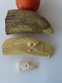 Three carved resin whale tooth carvings including: 2 eagle heads - the largest signed "Artek Replica