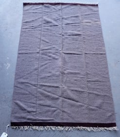 A woven gray wool blanket with single brown border on one end and a double brown border on the