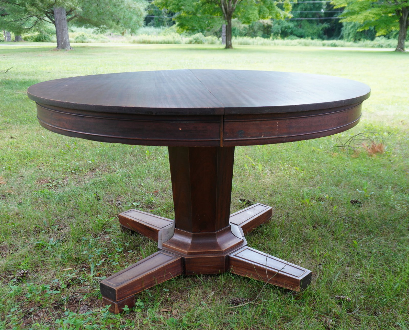 A mahogany dining table with 4 leaves on pedestal base with 4 extended feet, circa 1900. Some use: A mahogany dining table with 4 leaves on pedestal base with 4 extended feet, circa 1900. Some use wear, but overall good condition. Measures 48" diameter x 30"H. The leaves are 12"W.