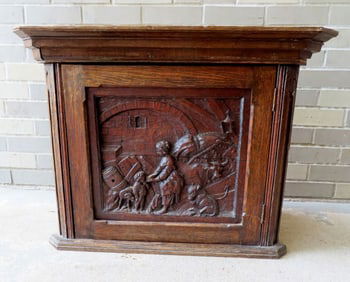 A European oak wall hanging corner cupboard with heavily carved front door depicting a cow with calf