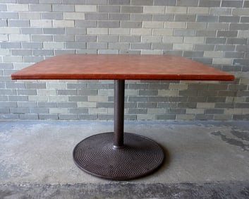 Mid-century modern style cafe table with a cast iron pedestal base supporting a faux grained