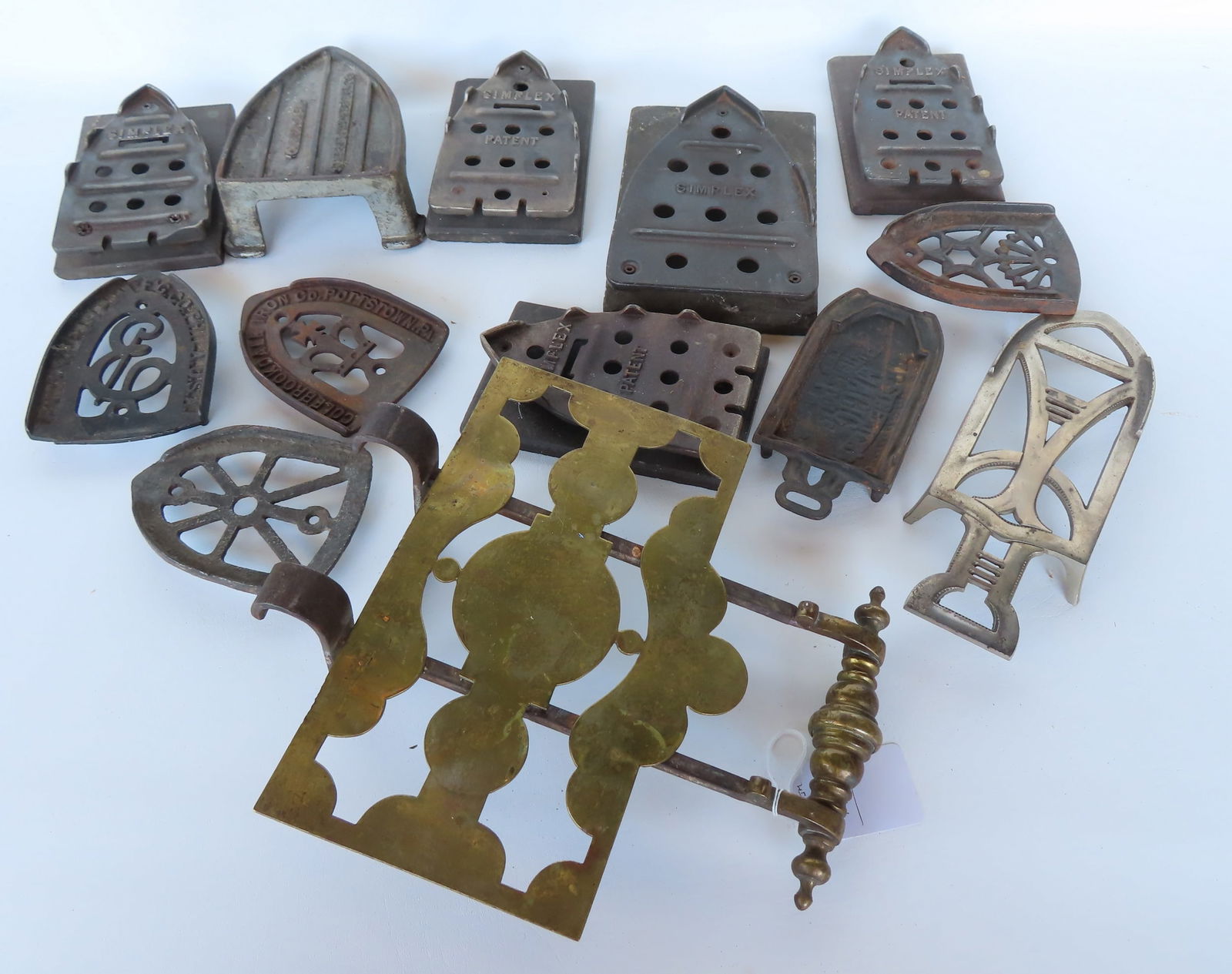 Large grouping of vintage iron trivets and an early adjustable brass and iron fireplace trivet,: Large grouping of vintage iron trivets and an early adjustable brass and iron fireplace trivet, early 19th century - 11 3/8"W x 12 3/4"L.