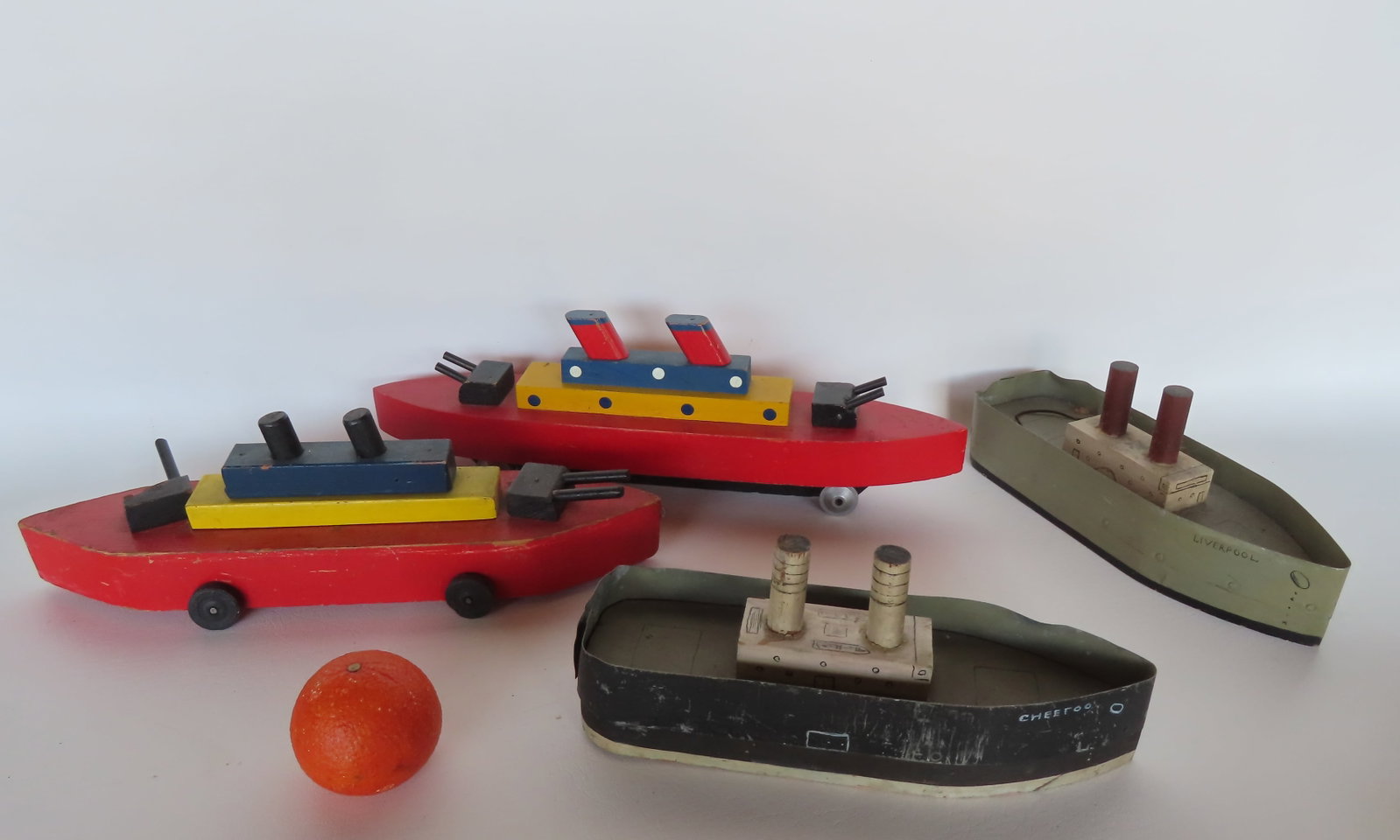 Grouping of 4 hand made vintage wooden boat models, the 2 with tin sides probably made by a child: Grouping of 4 hand made vintage wooden boat models, the 2 with tin sides probably made by a child circa 1950. One missing a barrel from gun turret, else very good condition. The largest measures 18"L 