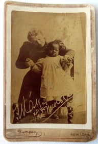 A cabinet card with lady holding an African American baby with inscription "Many & the Newest B….