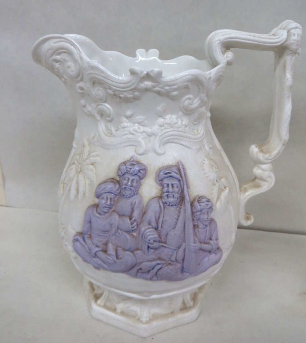 Two salt glazed English pitchers with raised decoration: Two salt glazed English pitchers with raised decoration, one signed Mintons with cherubs - 4", the other with embossed Middle Eastern gentlemen and palm trees - 8"H.