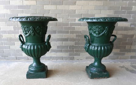 A matched pair of cast iron garden urns mounted on pedestal bases, in green paint. Early to mid 20th