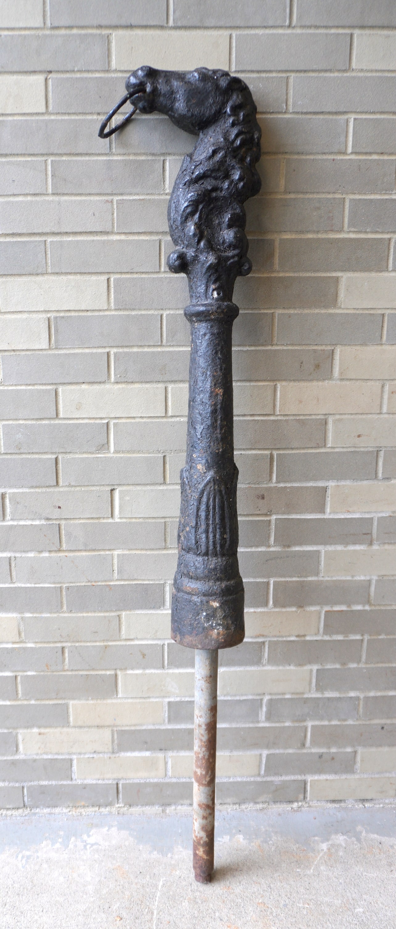 An unusual cast iron horse head hitching post with layers of old paint and having a rearing head,: An unusual cast iron horse head hitching post with layers of old paint and having a rearing head, 19th century, good condition. The base of the post with acanthus decorations. Measures 59 1/2"H (inclu
