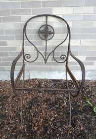 A hand made iron arm chair, the back splat decorated with a central flower. Appears to be hand