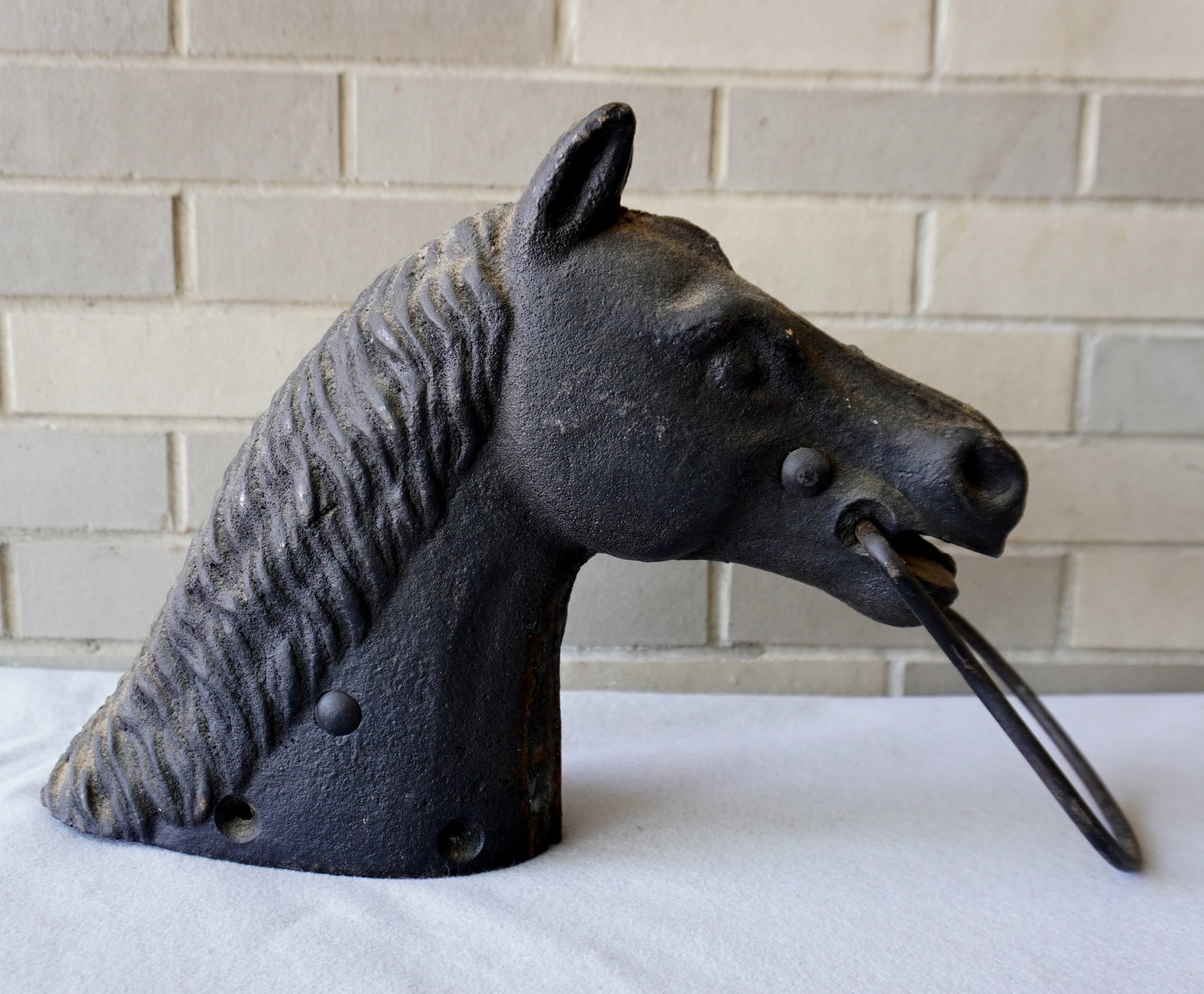A cast iron horse head hitching post, detailed mane and face, late 19th to early 20th century, good: A cast iron horse head hitching post, detailed mane and face, late 19th to early 20th century, good condition. A metal label attached, most illegible "Made xx(by) Gxx" - measures 13"D x 12 1/2"H x 5 3