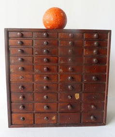 A 40 drawer walnut table top storage unit having 10 rows of 4 small drawers, graduated in size and