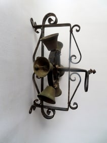 A wall mounted revolving wrought iron farmhouse bell decorated with applied scrolls and with 6 brass