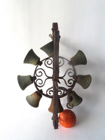 A wall mounted revolving wrought iron farmhouse bell decorated with applied scrolls, and with 8