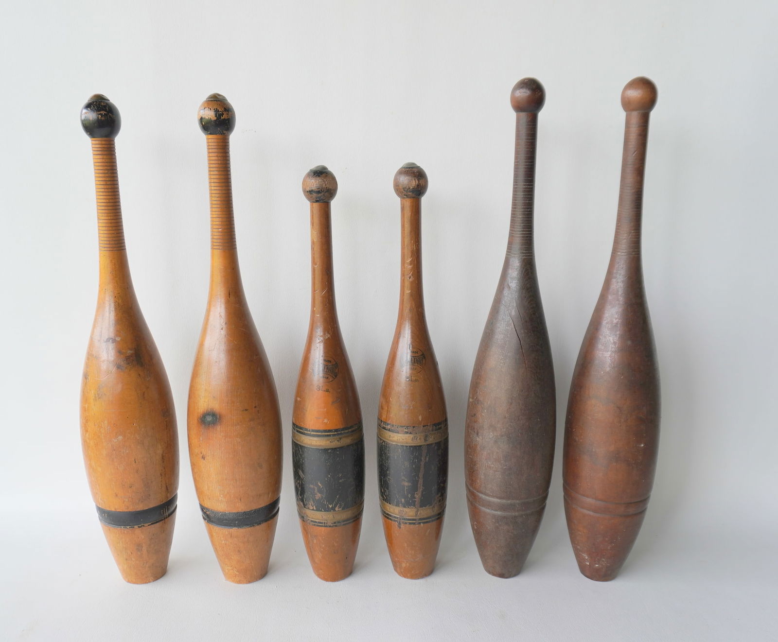 Three sets of vintage wooden Indian clubs, probably early 20th century. The first pair in maple with: Three sets of vintage wooden Indian clubs, probably early 20th century. The first pair in maple with original black painted highlights and metal caps - one pin with slight expansion crack, else both i