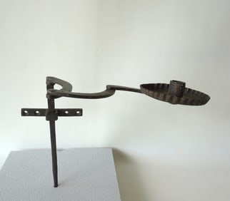 An unusual wall mounted hand forged iron candle lighting device with crimped edge to drip pan, and