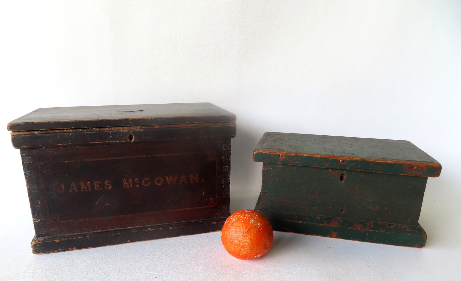 Two primitive hand made wooden document boxes in original paint. The first has oxidized to a dark: Two primitive hand made wooden document boxes in original paint. The first has oxidized to a dark green paint, dovetailed construction, and dated 1872 within diamond medallion on center of lid, and th