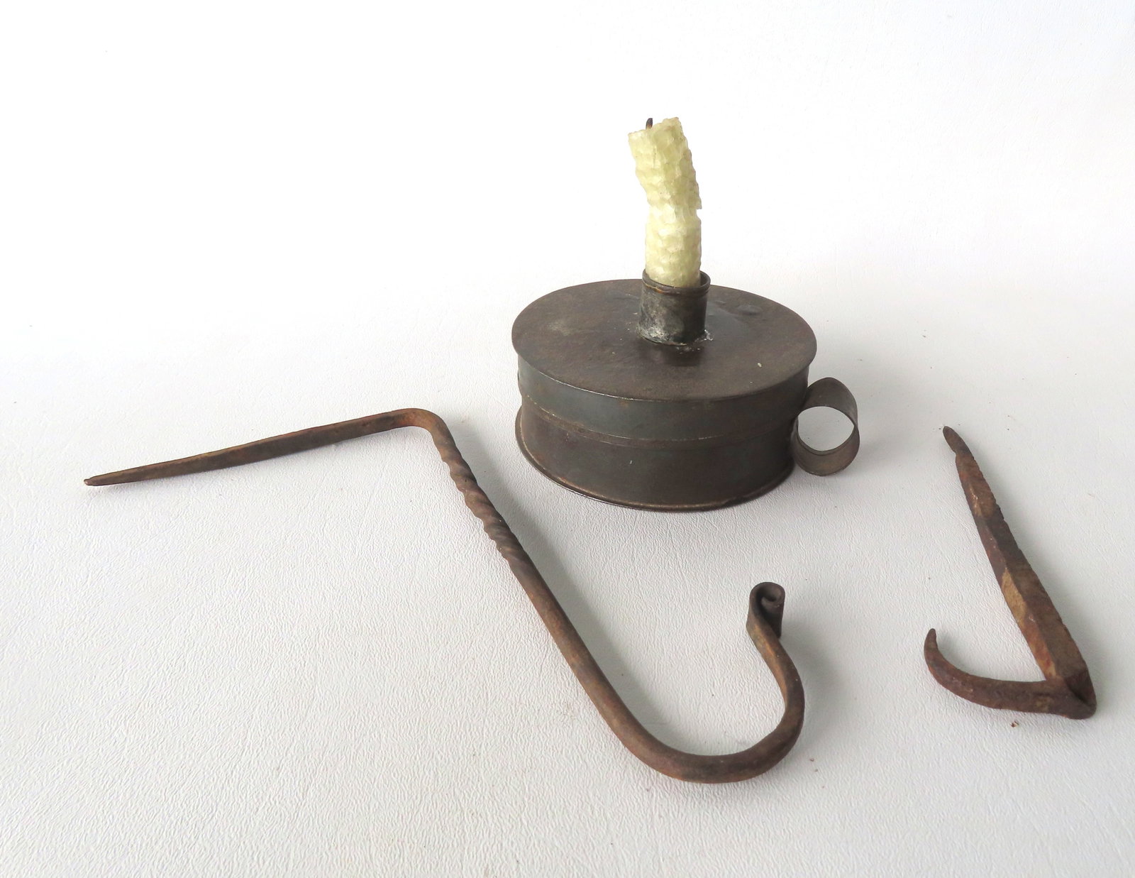 Three early lighting related tin and iron collectibles including: An early combination tin tinder: Three early lighting related tin and iron collectibles including: An early combination tin tinder box & chamber stick, with striker, flint, hand made wax candle, and interior lid. - measures 5"W x 1 7