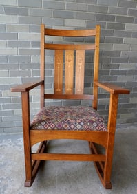 A Harvey Ellis style oak rocker having stylized floral inlays on back splats and with "Stickley