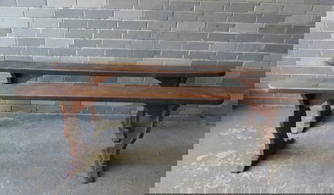 A pair of narrow wooden meeting house benches with trestle legs that are mortised through the top,