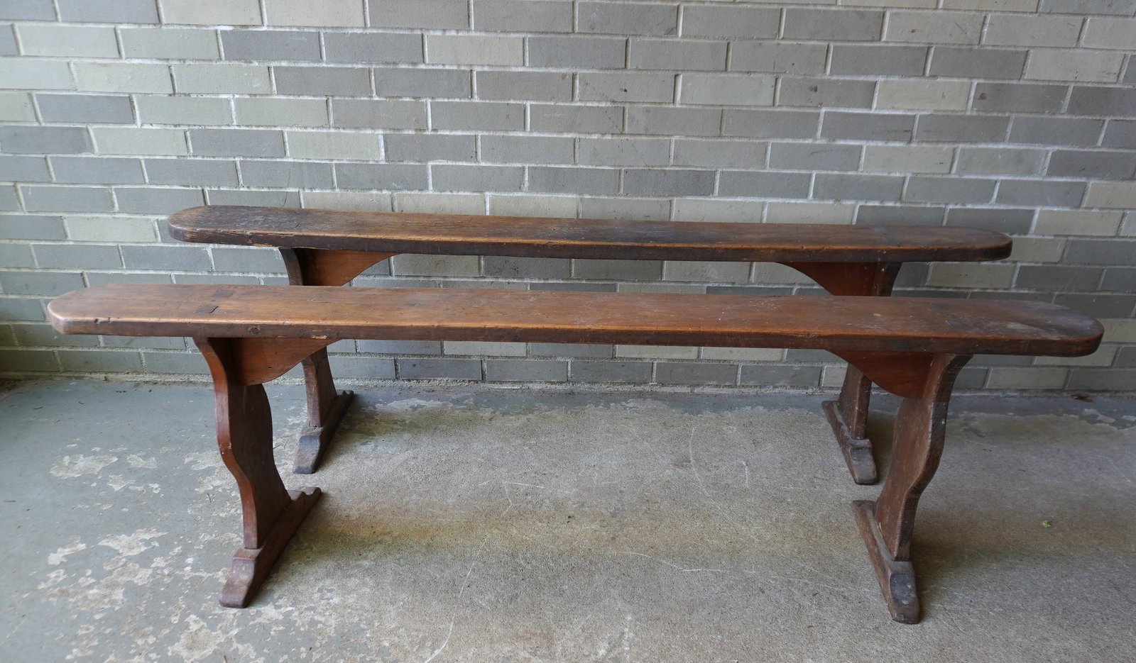 A pair of narrow wooden meeting house benches with trestle legs that are mortised through the top,: A pair of narrow wooden meeting house benches with trestle legs that are mortised through the top, and mortised into shoe feet and fastened with wooden dowels, mid to late 19th century. Both with use 