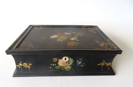 A black lacquered paper mache lap desk with slanted lid, decorated with hand painted flowers and