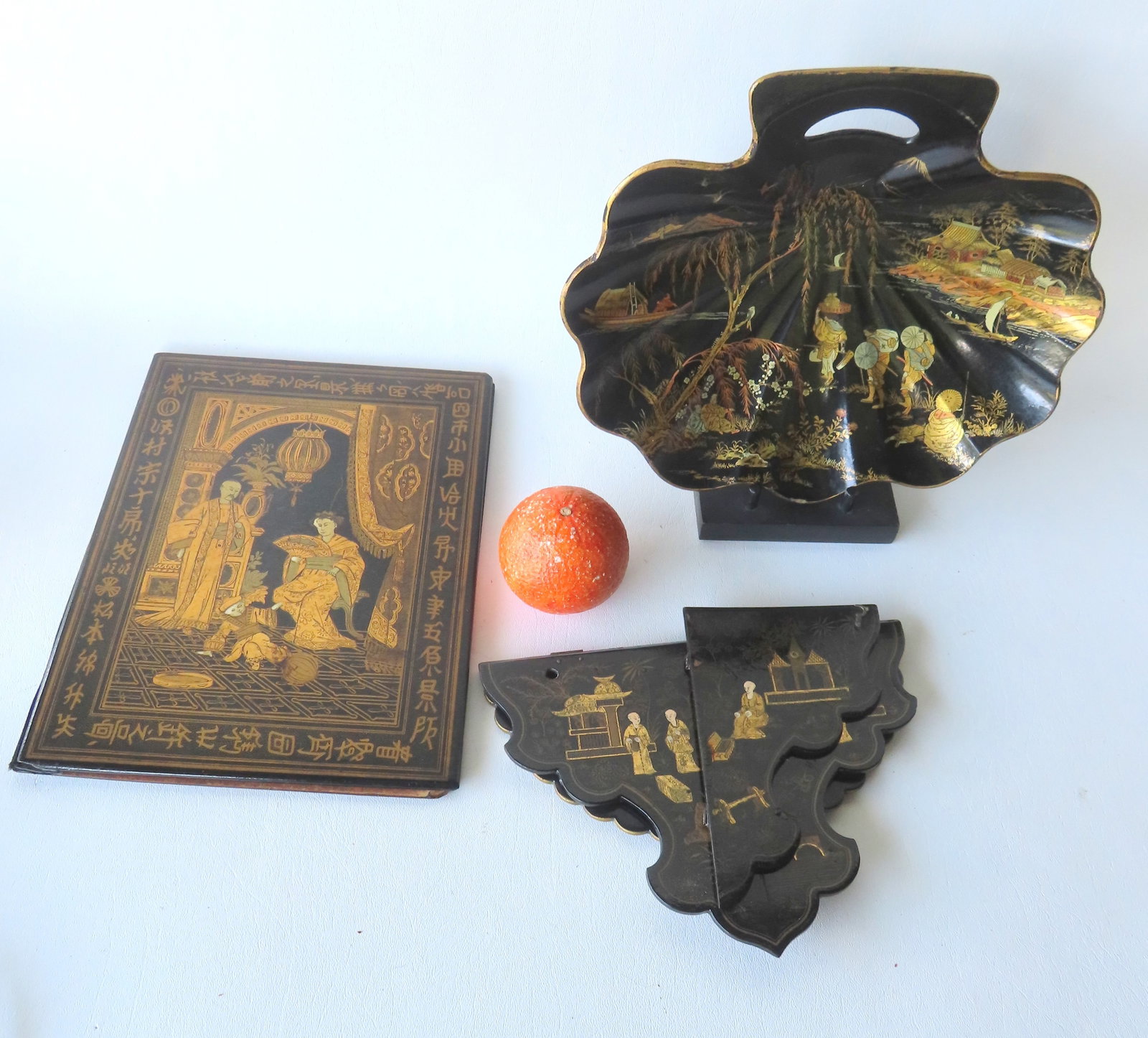 Three oriental black lacquered paper mache collectibles, all 19th century, including: Book covers: Three oriental black lacquered paper mache collectibles, all 19th century, including: Book covers with gilded image of oriental gentleman, lady and child in parlor setting - slight wear to corners, el