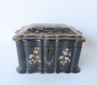 A black lacquered hand painted tea caddy with mother of pearl inlay, decorated with flowers and