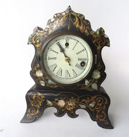 A cast iron shelf clock with black lacquered case decorated with gilding and mother of pearl inlays,