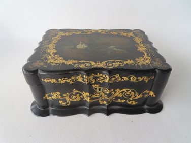 A Victorian black lacquered paper mache writing box. The lid with gilded flowers and scrolled wreath