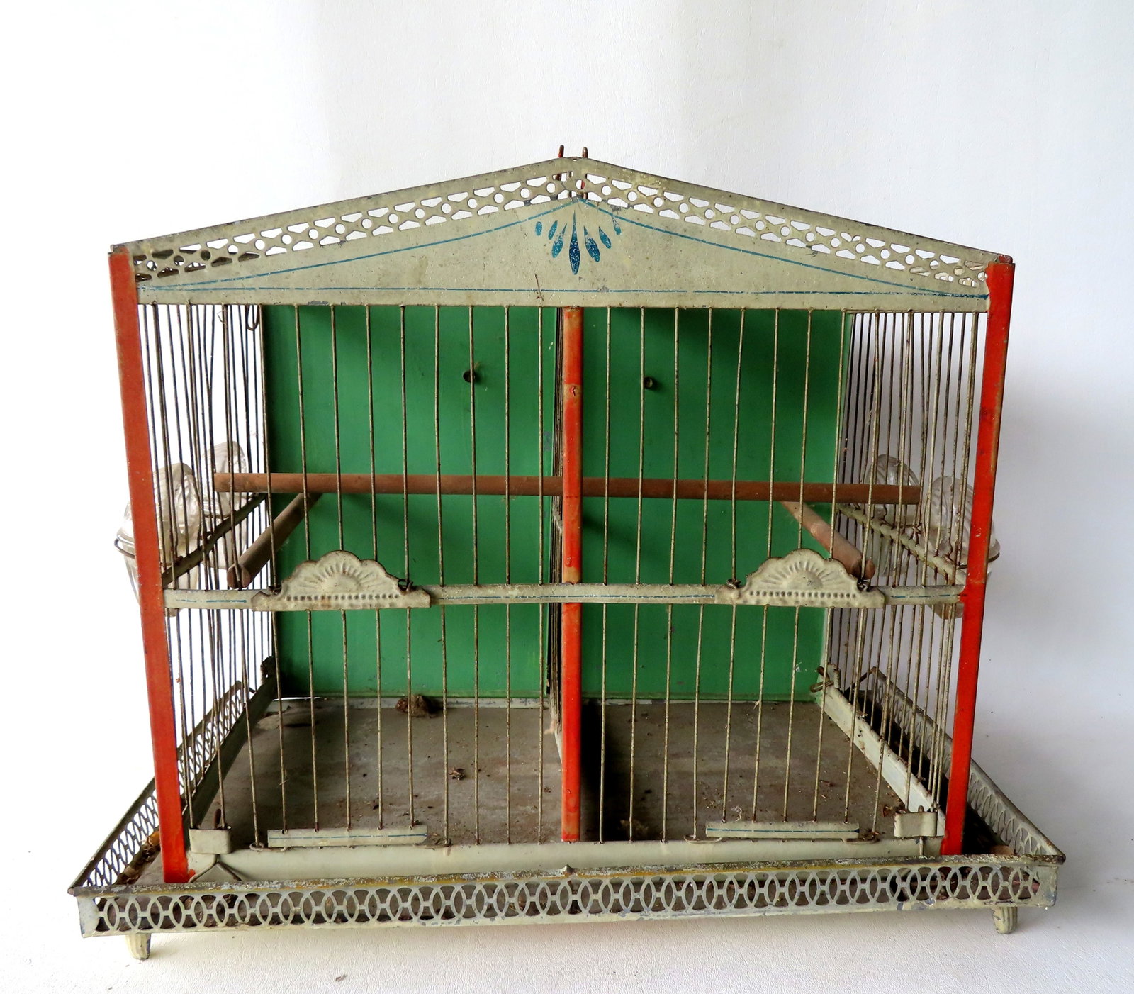 A good hanging or standing (footed base) toleware 2 section birdcage, late 19th century.: A good hanging or standing (footed base) toleware birdcage with salmon colored corners, light oxidized green ground and blue pinstripes, in original paint with 4 glass bird feeders and wooden perches.
