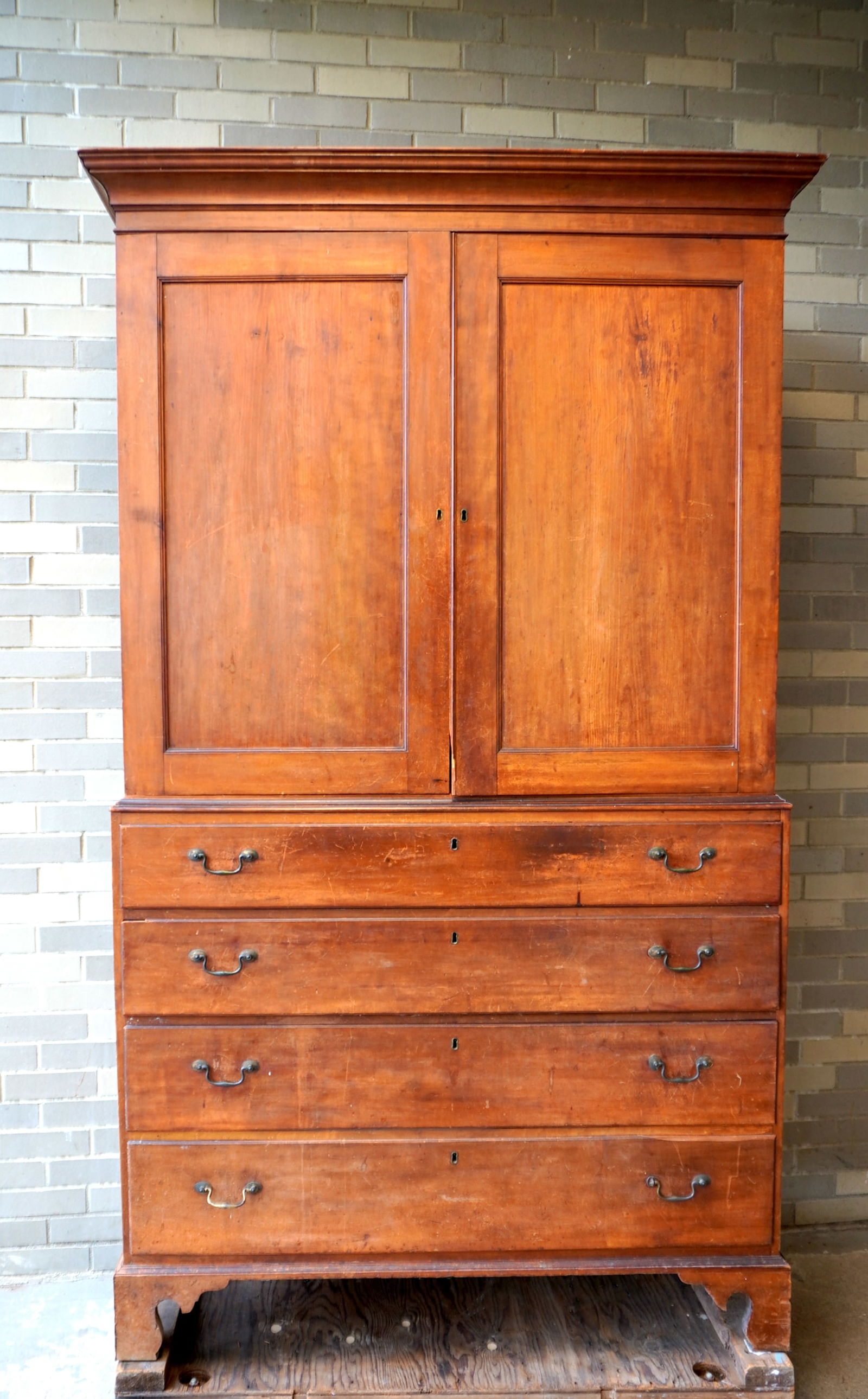 A cherry Chippendale 2 part linen press with cornice over 2 paneled doors over 4 graduated beaded: A cherry Chippendale 2 part linen press with cornice over 2 paneled doors over 4 graduated beaded and dovetailed drawers with original bale pulls and mounted on a good bracket base, late 18th century.