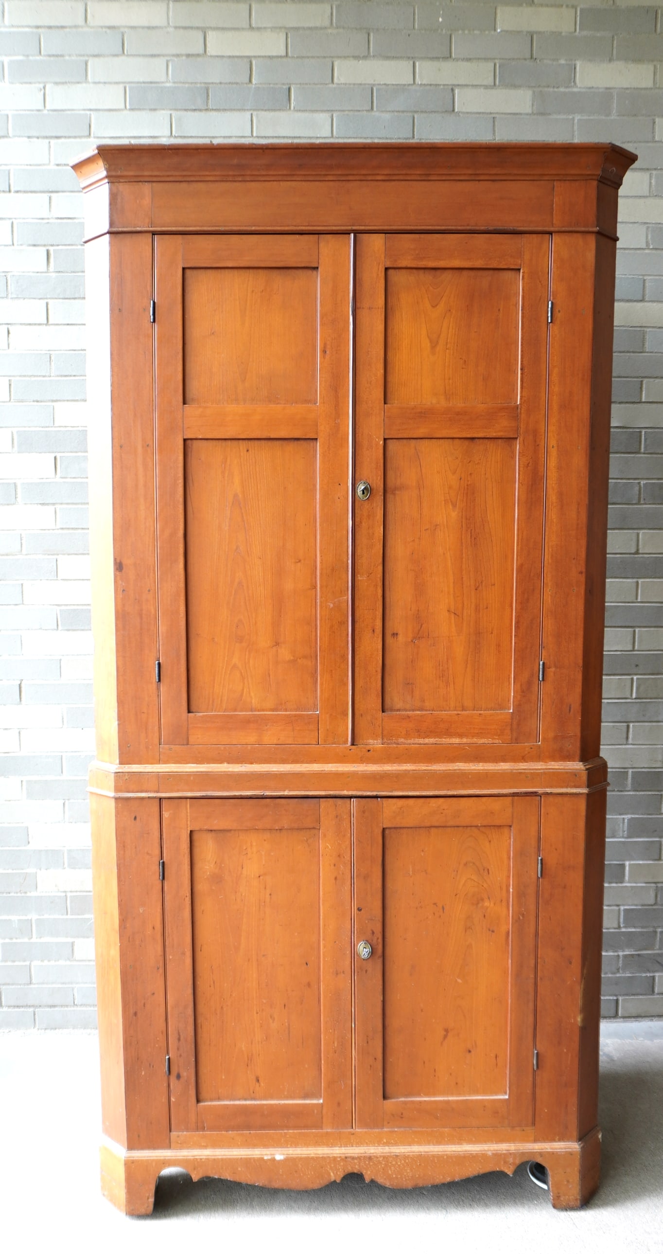 A Hudson Valley 2 part blind door cherry corner cupboard having 2 paneled doors over 2 paneled doors: A Hudson Valley 2 part blind door cherry corner cupboard having 2 paneled doors over 2 paneled doors and of good proportions - the top section with shaped shelves mounted on a shaped cutout base, earl