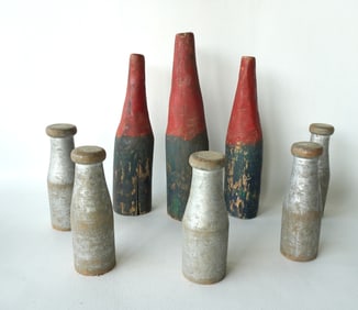 A grouping of 8 carnival knock-down bottles including: 5 in bottle form with weighted bases in