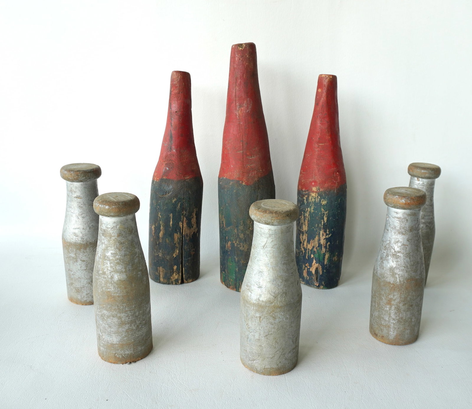 A grouping of 8 carnival knock-down bottles including: 5 in bottle form with weighted bases in: A grouping of 8 carnival knock-down bottles including: 5 in bottle form with weighted bases in original gray paint - all in good condition, early 20th century - each 7 1/4"H; and 3 also bottle shape b