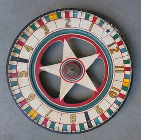 A vintage hand made double sided carnival gaming wheel in original paint, with a star shaped center,