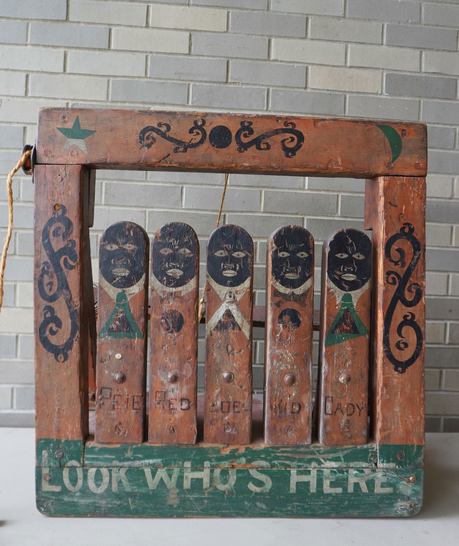 A folk art carnival carved wooden knock-down doll gallery game, in the form of 5 men of color, with: A folk art carnival carved wooden knock-down doll gallery game, in the form of 5 men of color, with writing at the base marked "LOOK WHO'S HERE " - the 5 dolls named "Peter, Red, Joe, Kid, and Cady",