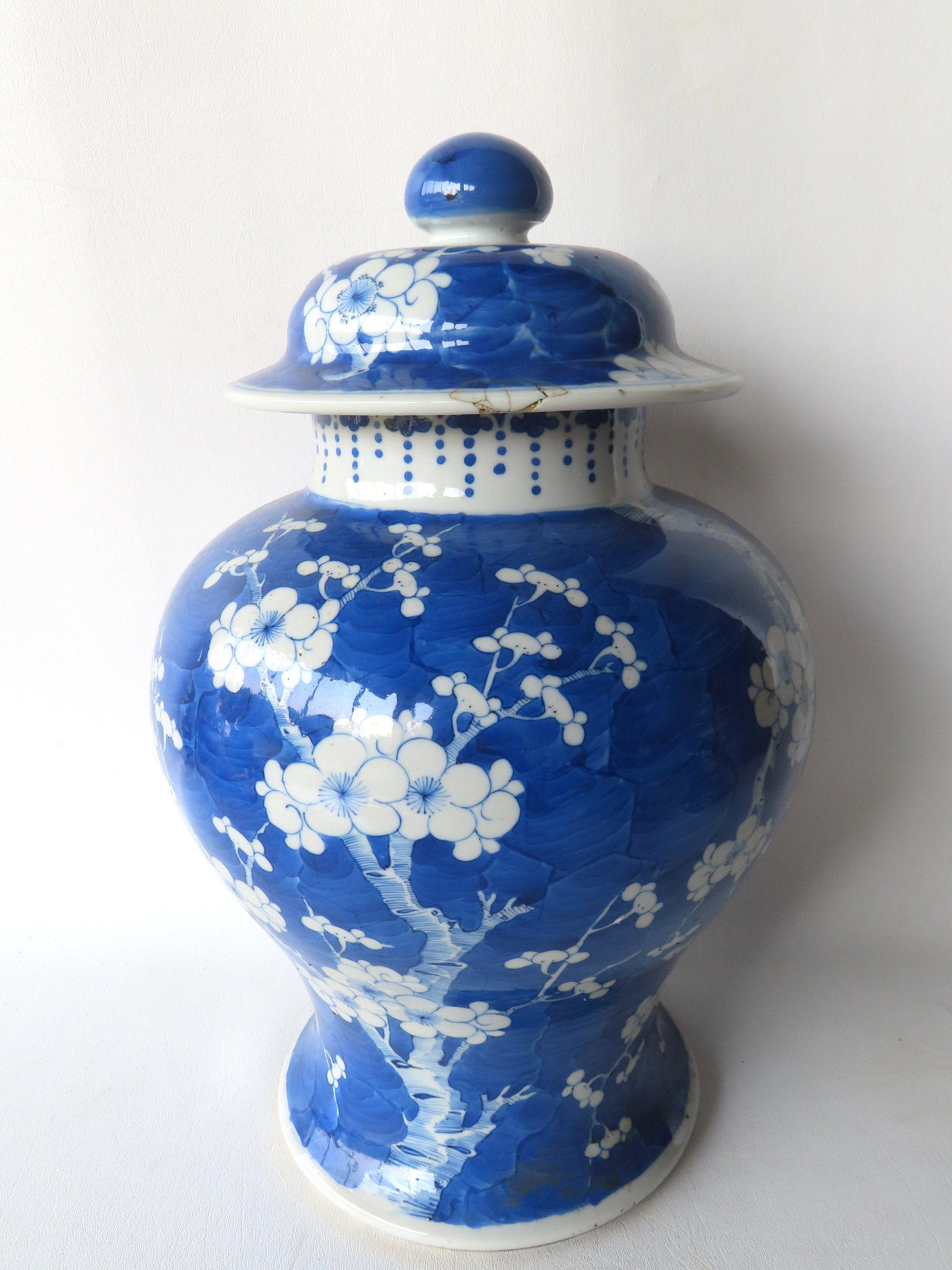 A large blue and white ginger jar in classic baluster form, having a domed lid with finial, and: A large blue and white ginger jar in classic baluster form, having a domed lid with finial, and decorated with a prunus tree and blossoms (plum tree). It has a double blue circle on the base, indicati