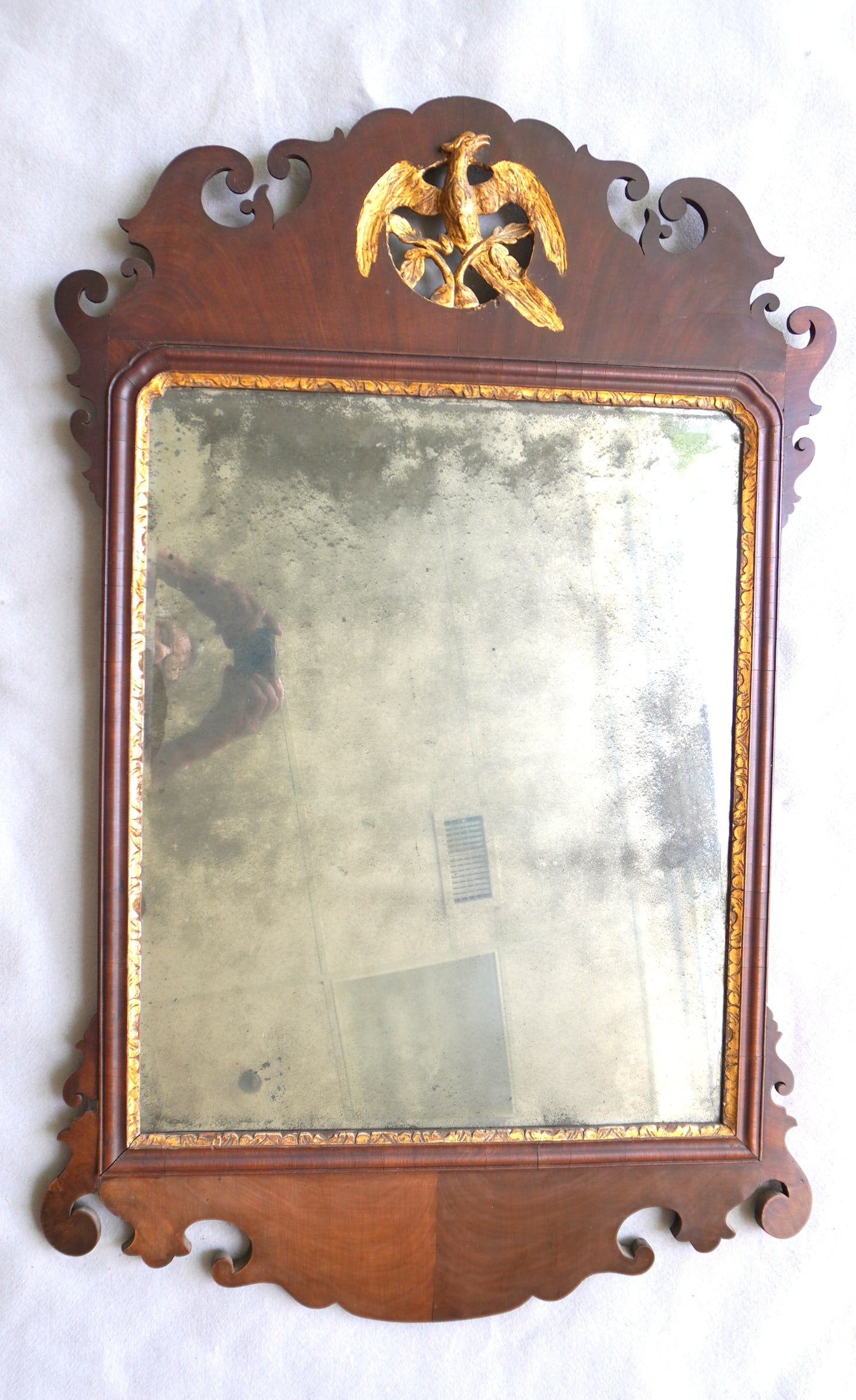 A Chippendale mahogany mirror with carved phoenix bird crest in original gilding, beveled glass, and: A Chippendale mahogany mirror with carved phoenix bird crest in original gilding, beveled glass, and with gilded wood inset, 18th century. Good condition with old finish and appears to retain original