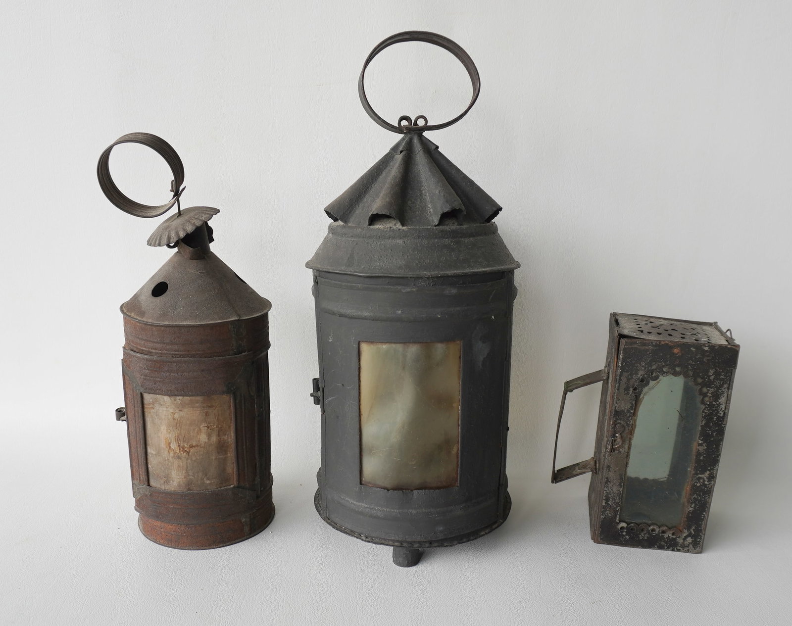 Three early tin candle lighting devices, late 18th to early 19th century. The first with original: Three early tin candle lighting devices, late 18th to early 19th century. The first with original mica glass panels in good condition; the second, the largest measuring 14 1/2"H (to top of handle) x 6