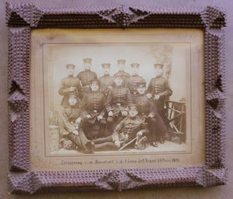 A tramp art frame currently holding a photo of soldiers from Germany, marked "Erinnerung a.m.