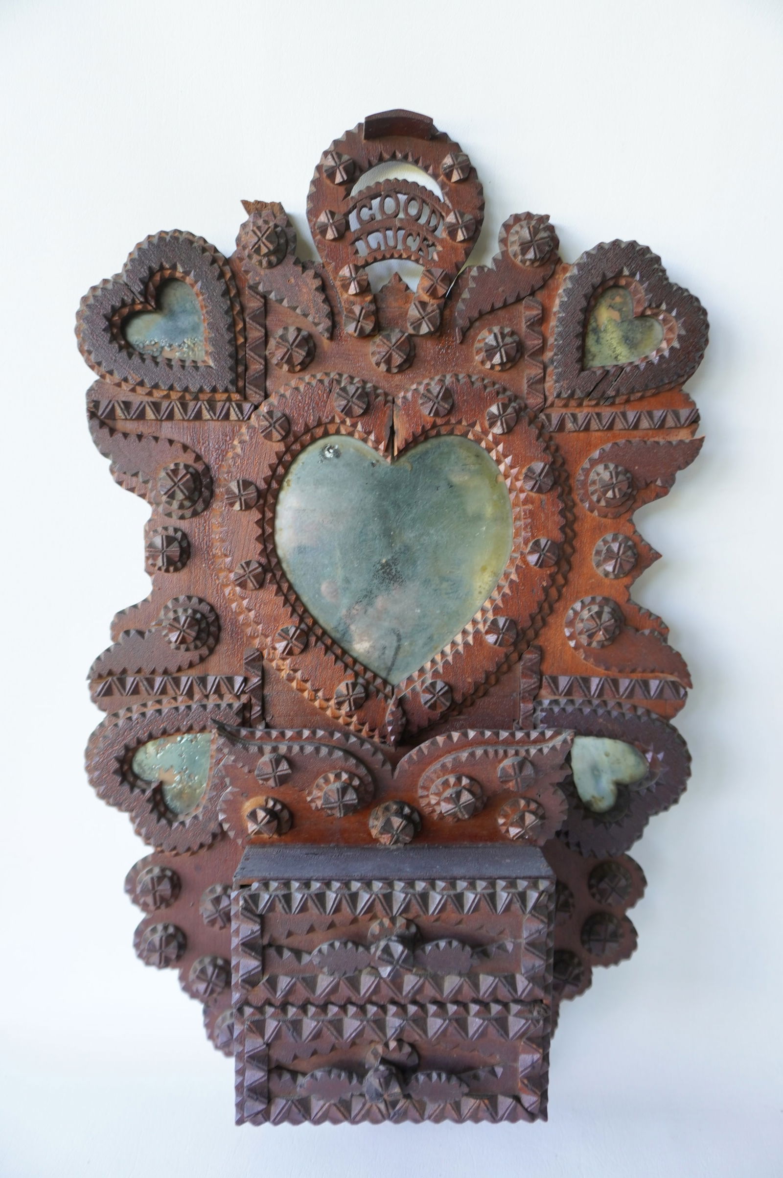 An exceptional lady's tramp art vanity wall mirror with attached wall box and 2 drawers. The mirror: An exceptional lady's tramp art vanity wall mirror with attached wall box and 2 drawers. The mirror is decorated with hearts and small circular flowers and having a horse-shoe finial encompassing the