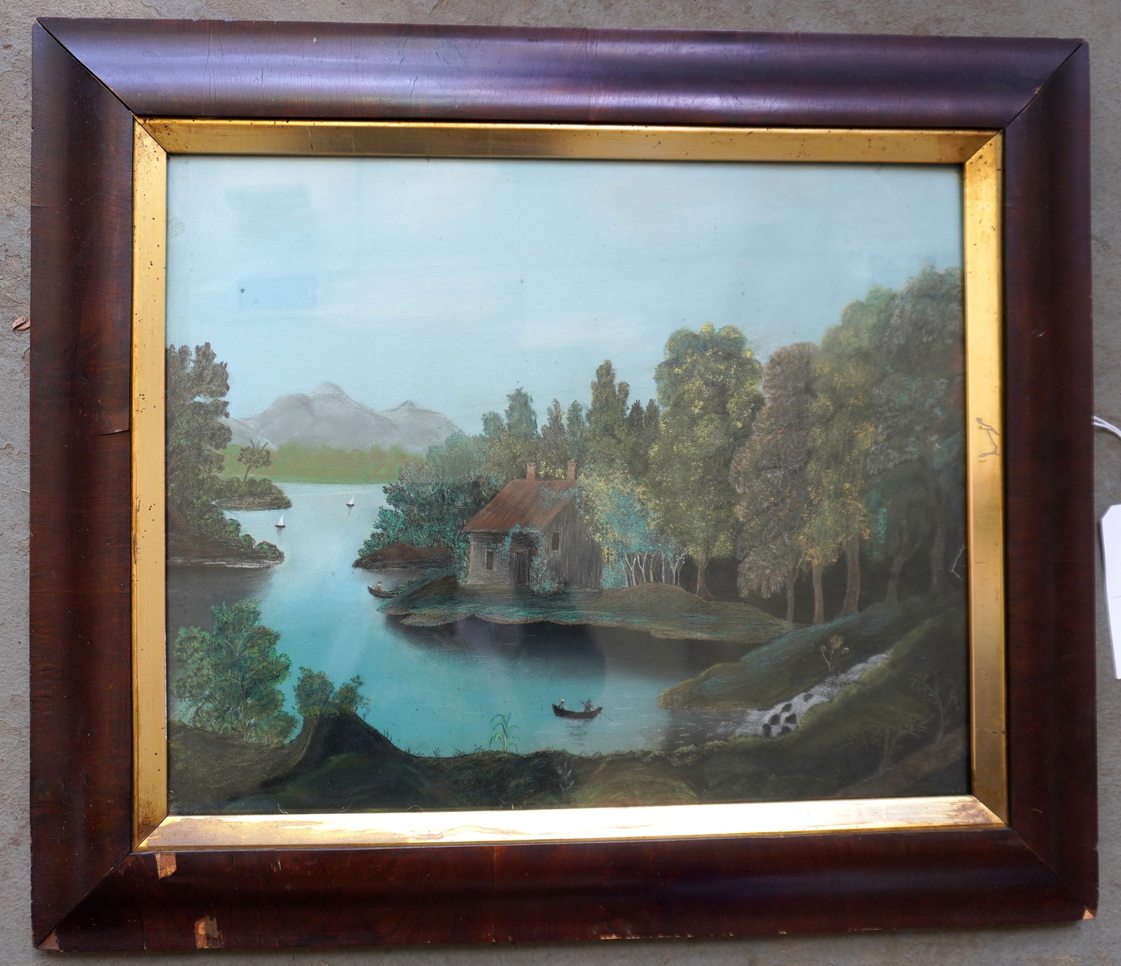 A pastel landscape sandpaper drawing, depicting stream flowing from mountain into lake with boats in: A pastel landscape sandpaper drawing, depicting stream flowing from mountain into lake with boats in water and cottage on shore, circa 1850 and housed within it's original ogee mahogany frame with gol