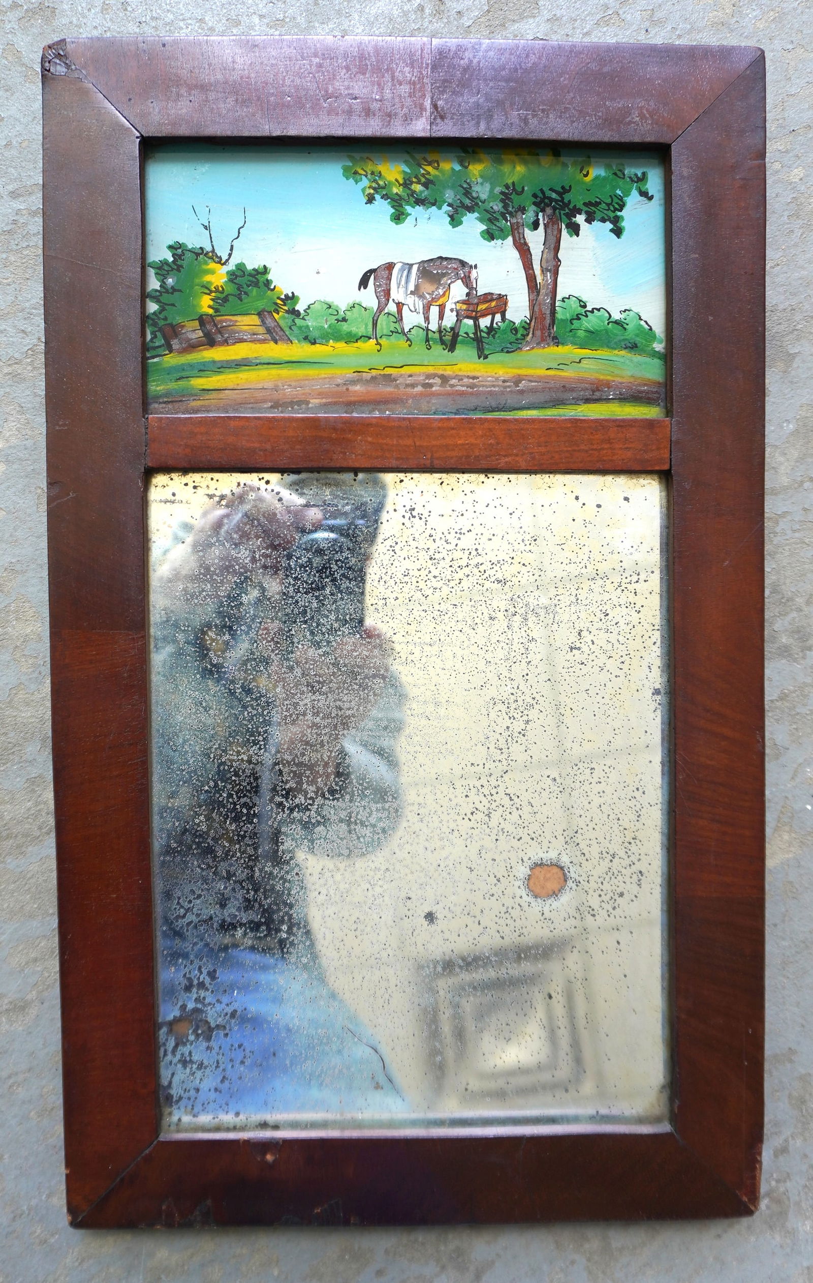 A small double panel Sheraton wall mirror. The upper panel with reverse painting of horse drinking: A small double panel Sheraton wall mirror. The upper panel with reverse painting of horse drinking from trough under a large tree, early to mid 19th century. Some losses to silvering backing mirror, e