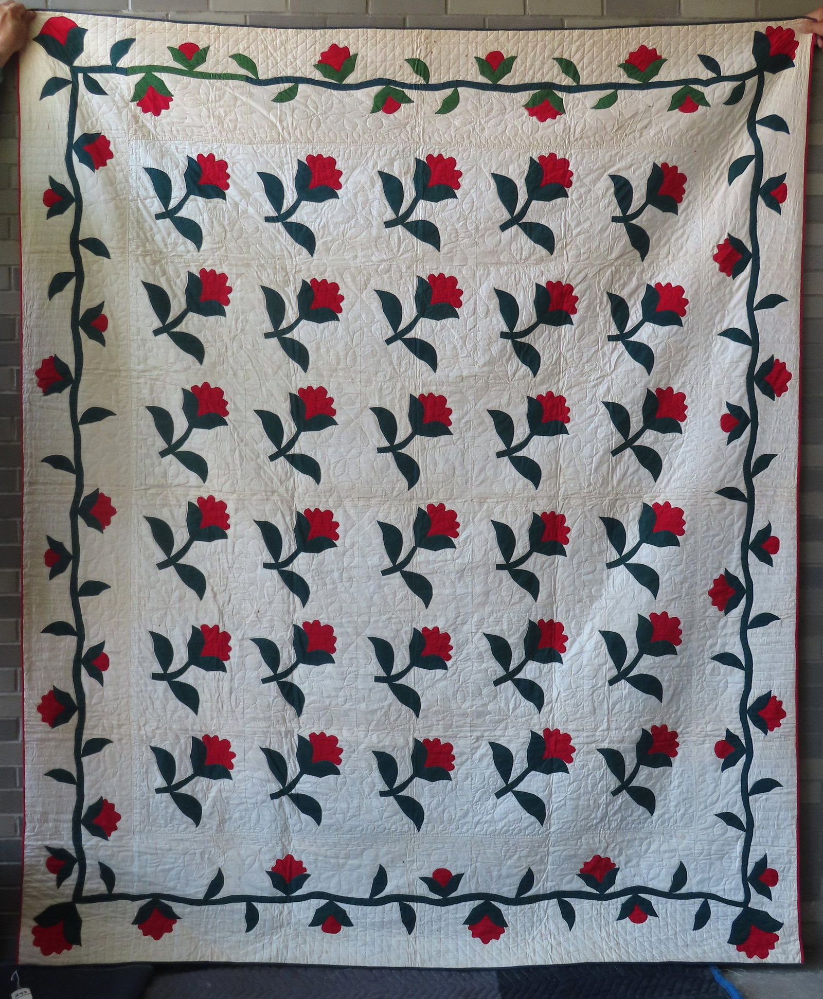 A high quality floral applique quilt, "Tulip" pattern, having a border decorated with flowers on: A high quality floral applique quilt, "Tulip" pattern, having a border decorated with flowers on vine. Appears unused, minor small brown stains, and overall very good condition, late 19th century. Mea