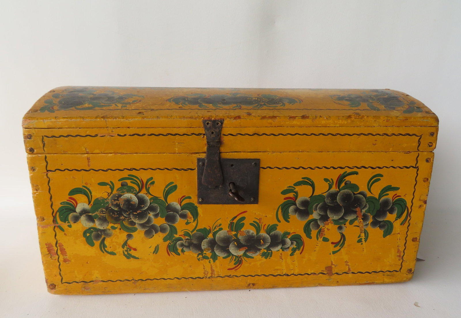 A New England dome top box in original mustard paint with leaf and berry paintings (probably: A New England dome top box in original mustard paint with leaf and berry paintings (probably stenciled), circa 1850. Retains original iron handles with back plates and original lock but non-working. C