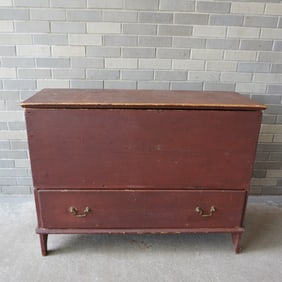 An early blanket chest in original red stain with cotterpin hinges on lid with molded edge over