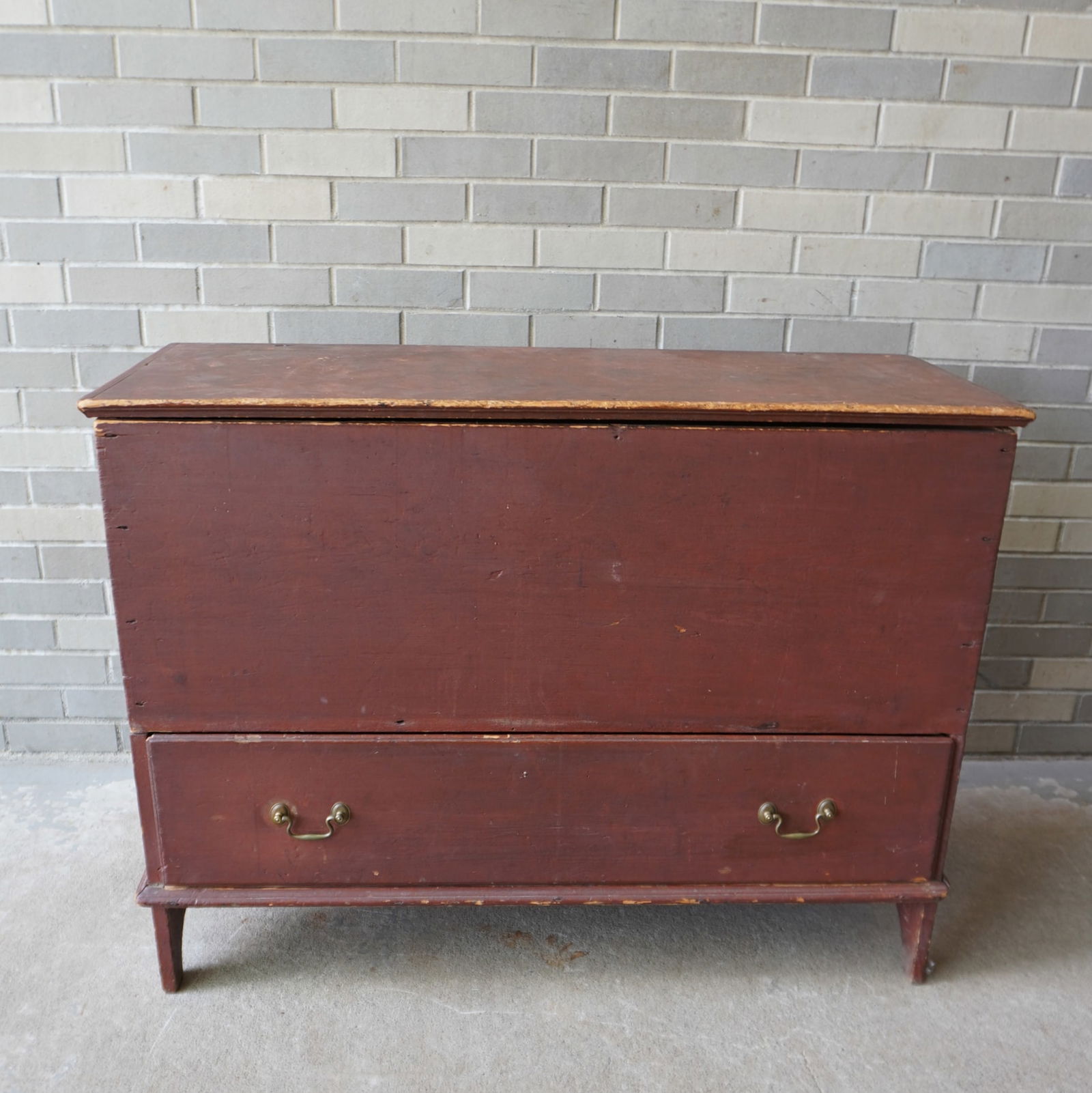 An early blanket chest in original red stain with cotterpin hinges on lid with molded edge over: An early blanket chest in original red stain with cotterpin hinges on lid with molded edge over single drawer with beaded edge, and early brass pulls that appear to be original, and mounted on high cu