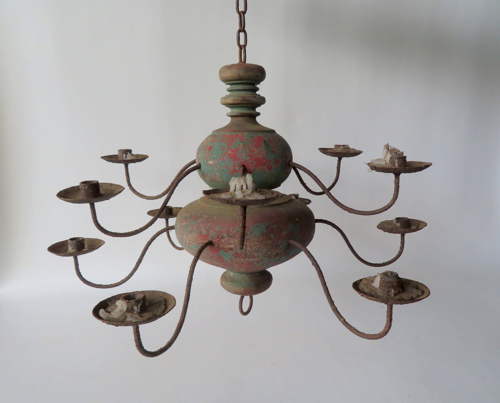A primitive style ceiling candelabra, 2 tiers of 6 candle fonts attached to a bulbous turned wooden: A primitive style ceiling candelabra, 2 tiers of 6 candle fonts attached to a bulbous turned wooden post, and traces of original blue paint over a red stain. Barn found and needs cleaning, unsure of a