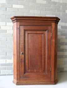 An early English oak hanging corner cupboard, with a molded paneled door with shaped shelves on